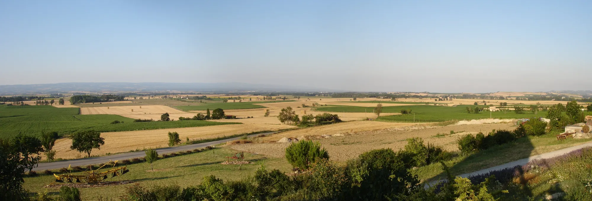 Les collines du Lauragais, champs de blé coupés et bosquets, sous un ciel clair